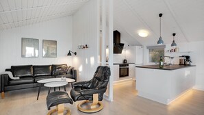Een modern interieur met een zwarte leren bank, een lederen fauteuil en een kleine ronde tafel.