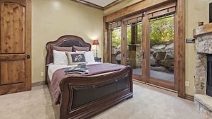 Une chambre avec un grand lit, une armoire en bois et une cheminée en pierre.