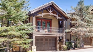 Une maison à deux étages avec un balcon, un garage et une entrée en pierre.