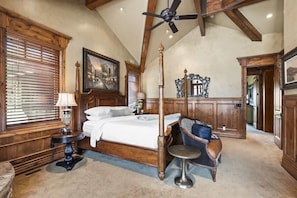 Une chambre à coucher avec un lit à baldaquin, une table de chevet, une chaise, un ventilateur de plafond et un lambris en bois.