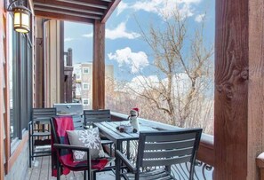 A covered outdoor seating area with a table and chairs, a snowman decoration, and a view of buildings and trees. - Abode at Angus House, private hot tub, at PCMR base (Park City)