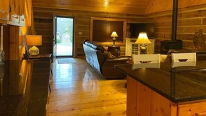 Ein gemütliches Blockhaus-Interieur mit Holzboden, einer Couch, einem Esstisch und einem Kamin.