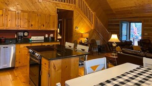 Ein Interieur einer Holzhütte mit Küche, Essbereich und einer Treppe.