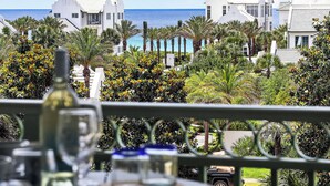 Vista de un resort con edificios blancos, palmeras y un cielo azul despejado.