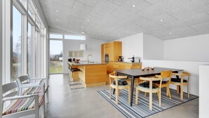 A modern kitchen with a central island, wooden cabinets, and a dining area with a striped rug.
