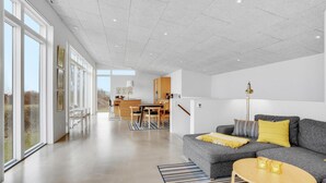 A spacious living area with a grey sofa, yellow pillows, and a striped rug.