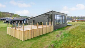 A modern wooden deck attached to a contemporary building with large windows.