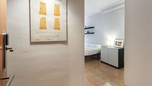 A hotel room with a bed, a small bedside table, a nightstand, and a poster on the wall.