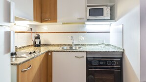 A compact kitchen with a microwave, sink, and coffee maker.