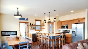 Una cocina moderna con armarios de madera, un refrigerador de acero inoxidable y un comedor con mesa y sillas de madera.