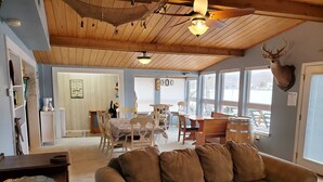 A cozy living room with a brown couch, wooden ceiling, and a mounted deer head. - Lake House with Multiple Decks and Large Swim Platform on Private Dock, (Rocky Mount)