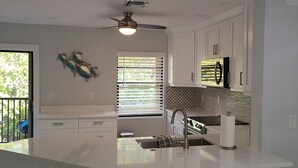 A modern kitchen with a central island, white cabinetry, and a ceiling fan.