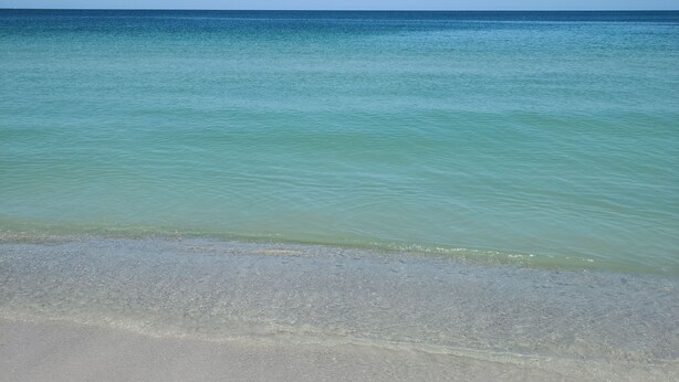 A beach with clear turquoise water and a sandy shore.