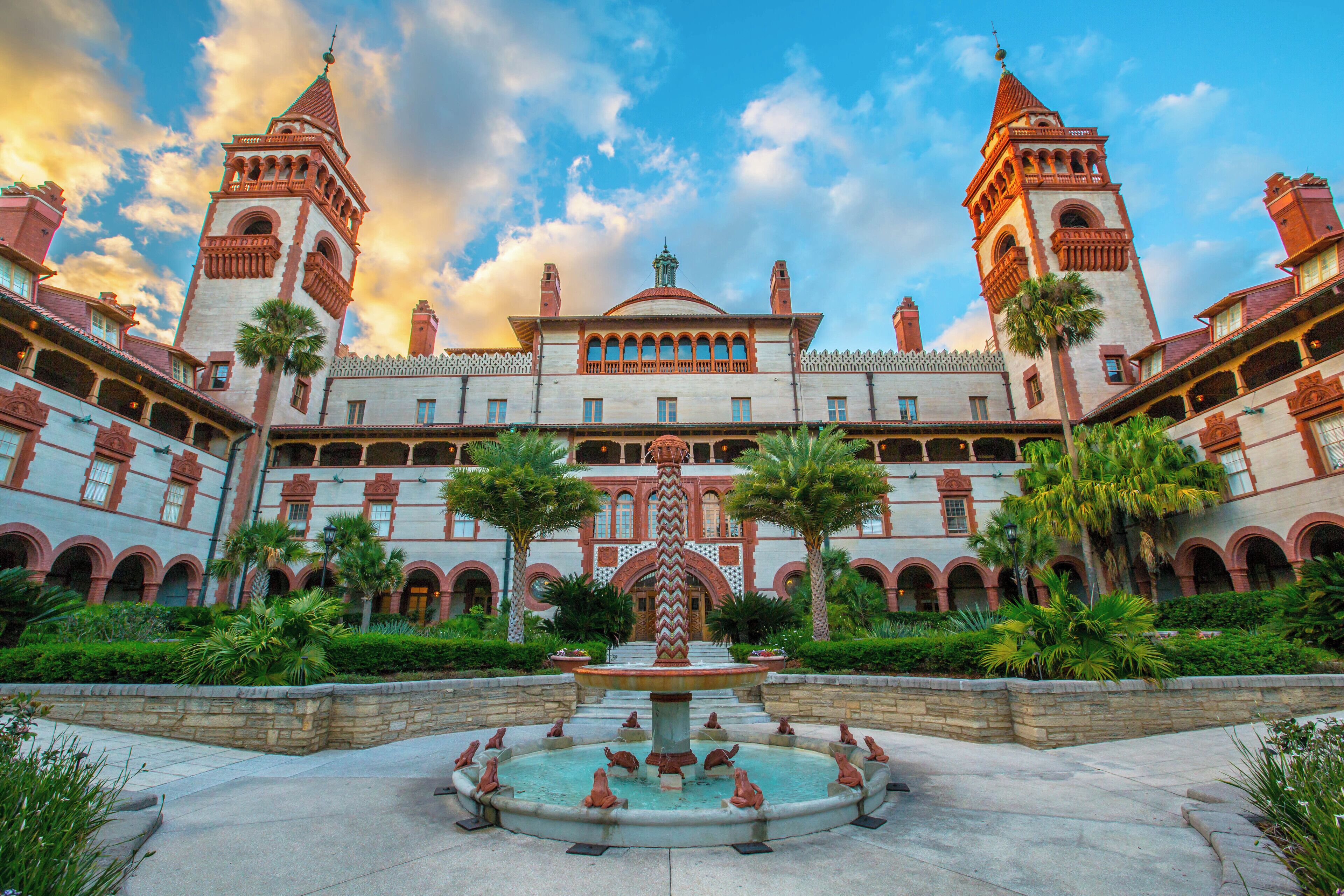 A historic building with a central courtyard, a fountain, and two towers.