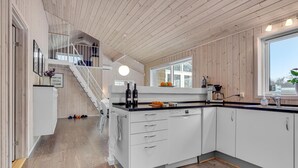A modern kitchen with white cabinets, a wooden floor, and a staircase leading to an upper level. - Cozy home in ålbæk with kitchen (Ålbæk)