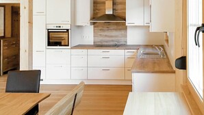 Una cucina moderna con mobili bianchi, forno integrato, piano di lavoro in legno e lavello.