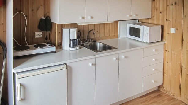 Une cuisine compacte avec des meubles blancs, un four à micro-ondes, une machine à café et un lave-vaisselle.