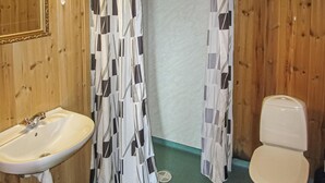 Une salle de bain avec un mur en bois, un lavabo blanc avec un robinet doré et des toilettes.