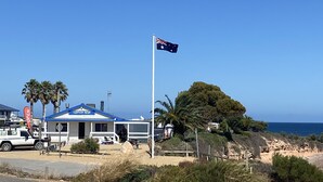 En fastighet vid kusten med en flagga, en byggnad med ett blått tak och en sandstrand.
