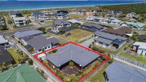 Zona residencial con casas, un patio cercado y vista al océano.
