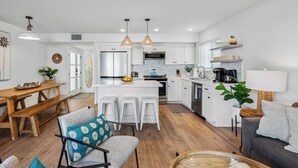 A modern kitchen with white cabinets, a central island, and pendant lighting. - 28th Street Beach House steps to sand, Air Conditioning, beach gear provided!   (Newport Beach)