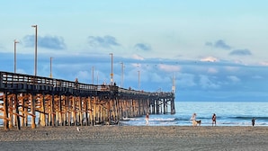 A pier extending into the sea with people walking along it and the beach in the foreground. - 28th Street Beach House steps to sand, Air Conditioning, beach gear provided!   (Newport Beach)