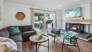 A modern living room with a fireplace, a sofa set, and a coffee table. - 28th Street Beach House steps to sand, Air Conditioning, beach gear provided!   (Newport Beach)