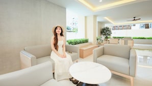 A modern interior with a woman seated on a sofa, a round table, and a ceiling fan. - B2 Huai Khwang Boutique & Budget Hotel (Bangkok)