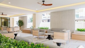 A modern lounge area with sofas, tables, and ceiling fans. - B2 Huai Khwang Boutique & Budget Hotel (Bangkok)