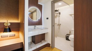 Un baño moderno con tocador, espejo de marco circular, ducha y retrete.