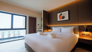 Un hotel moderno con una cama grande, vistas desde un balcón y un cuadro abstracto enmarcado en la pared.