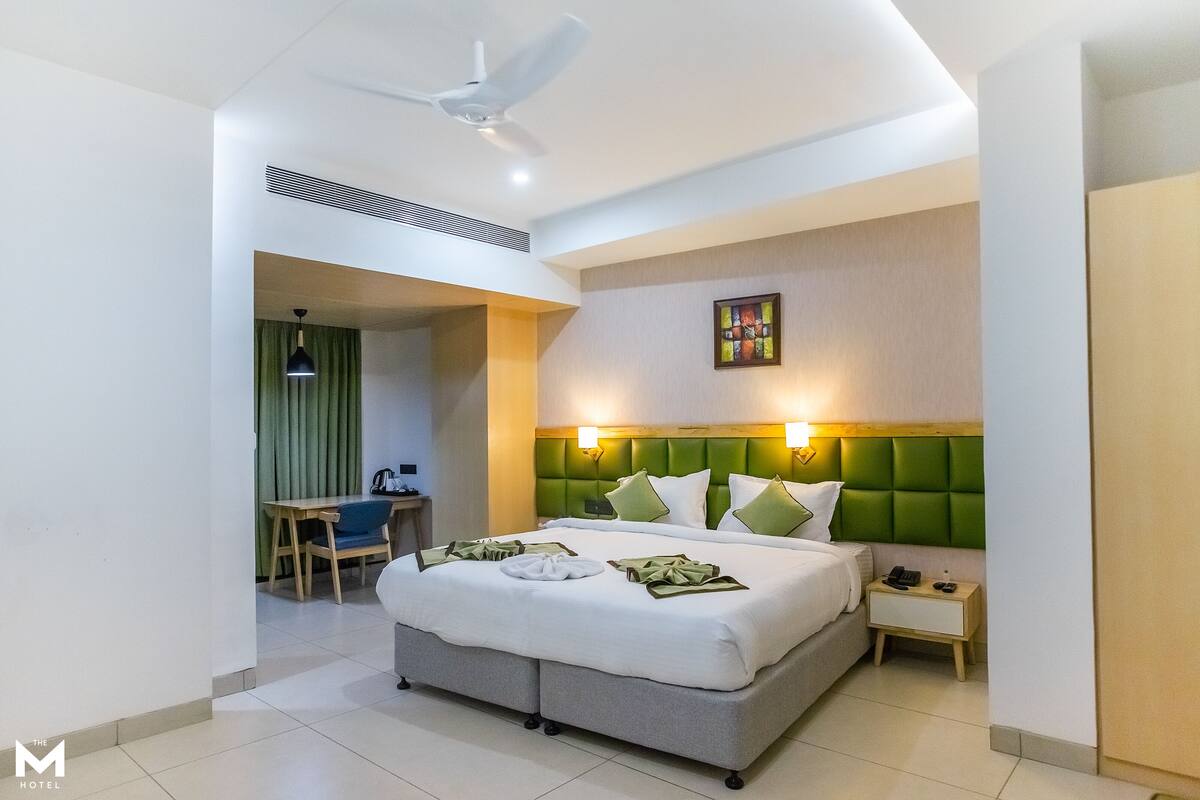 A hotel room with a large bed, a desk, and a chair.