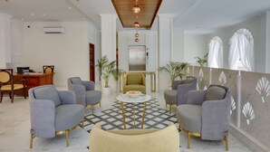 A modern lobby with grey armchairs, a marble coffee table, and a wooden ceiling. - Dev Panache (Udaipur)