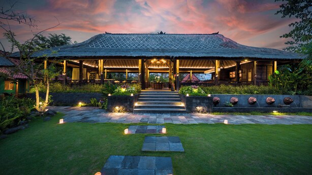 A traditional-style building with a thatched roof, a stone pathway leading to the entrance, and a well-maintained garden. - Villa Kapungkur (Jimbaran)