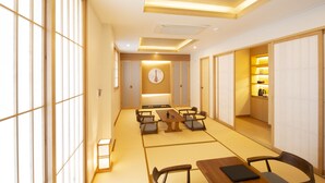A traditional Japanese-style room with tatami flooring, a low table with cushions, and sliding doors leading to a kitchen area. - Tomonoya Hotel & Ryokan Gyeongju (Gyeongju)