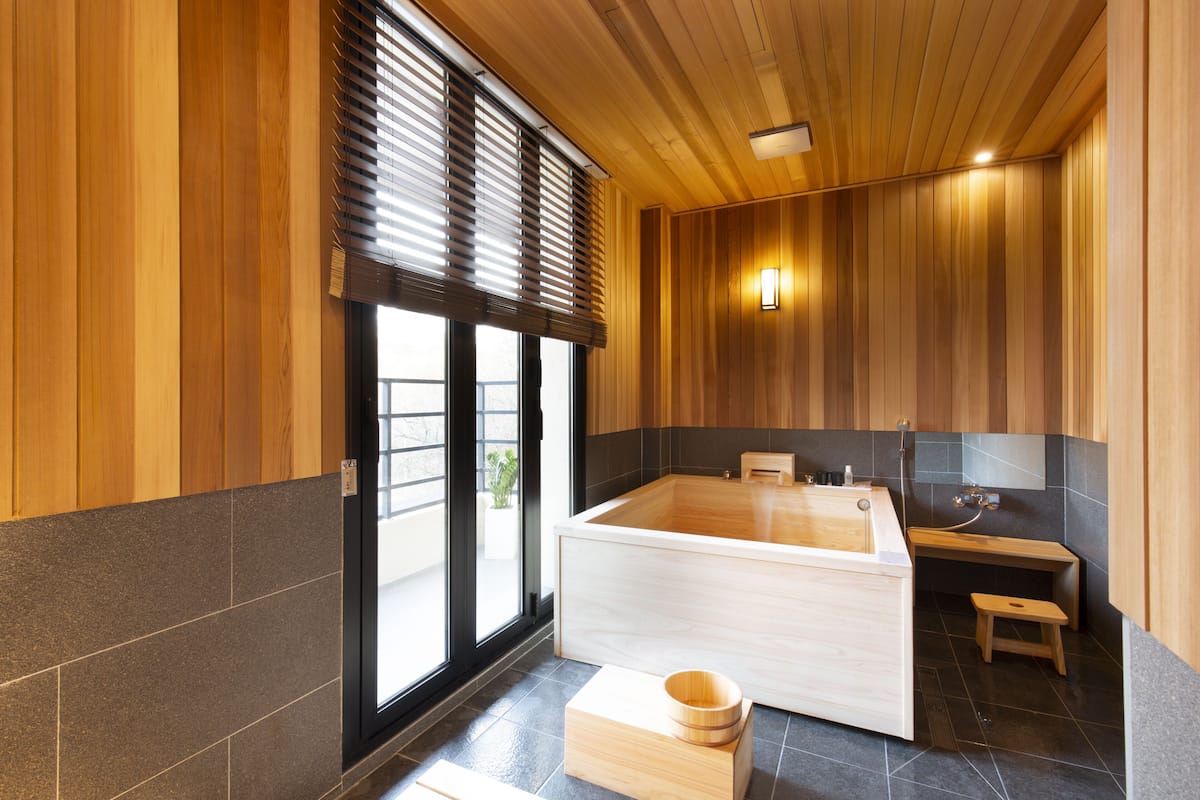 A modern bathroom with a large bathtub, wooden paneling, and a small wooden stool.