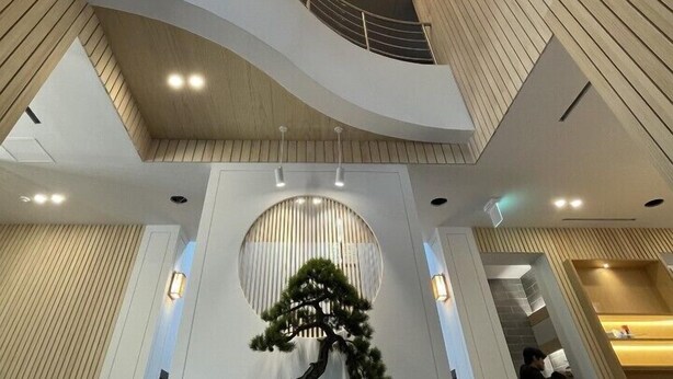 A modern interior with a central staircase, a circular skylight, and a bonsai tree. - Tomonoya Hotel & Ryokan Gyeongju (Gyeongju)