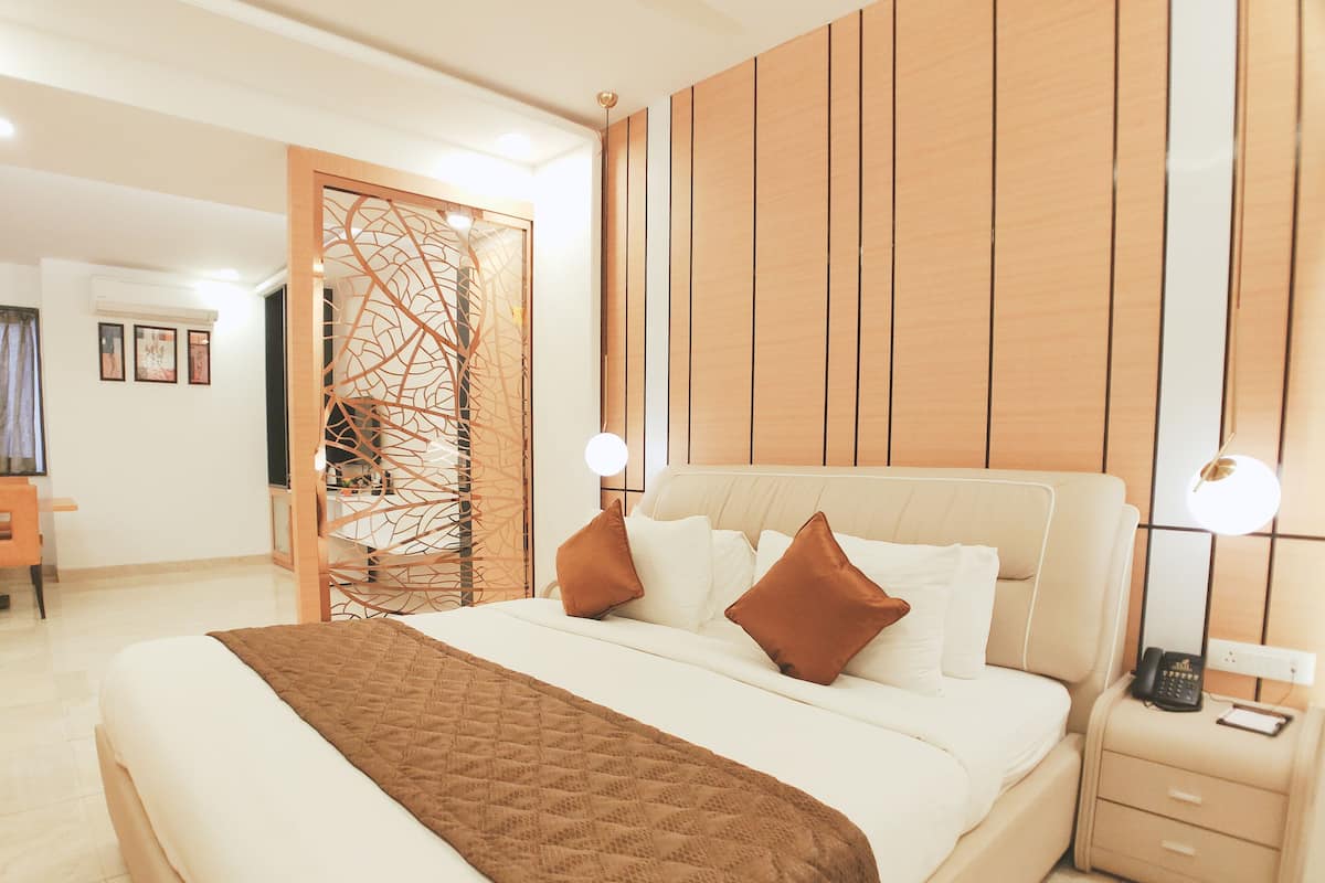 A modern bedroom with a large bed, bedside tables, a wooden partition, and a desk area.