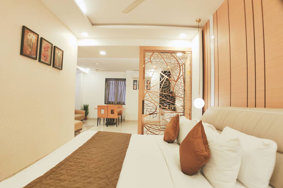 A modern bedroom with a bed, a wooden partition, a dining area, and a ceiling fan.