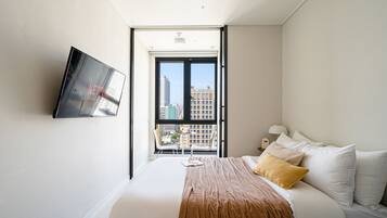 Een hotelkamer met een bed, een aan de muur bevestigde televisie en een raam met uitzicht op de stad.