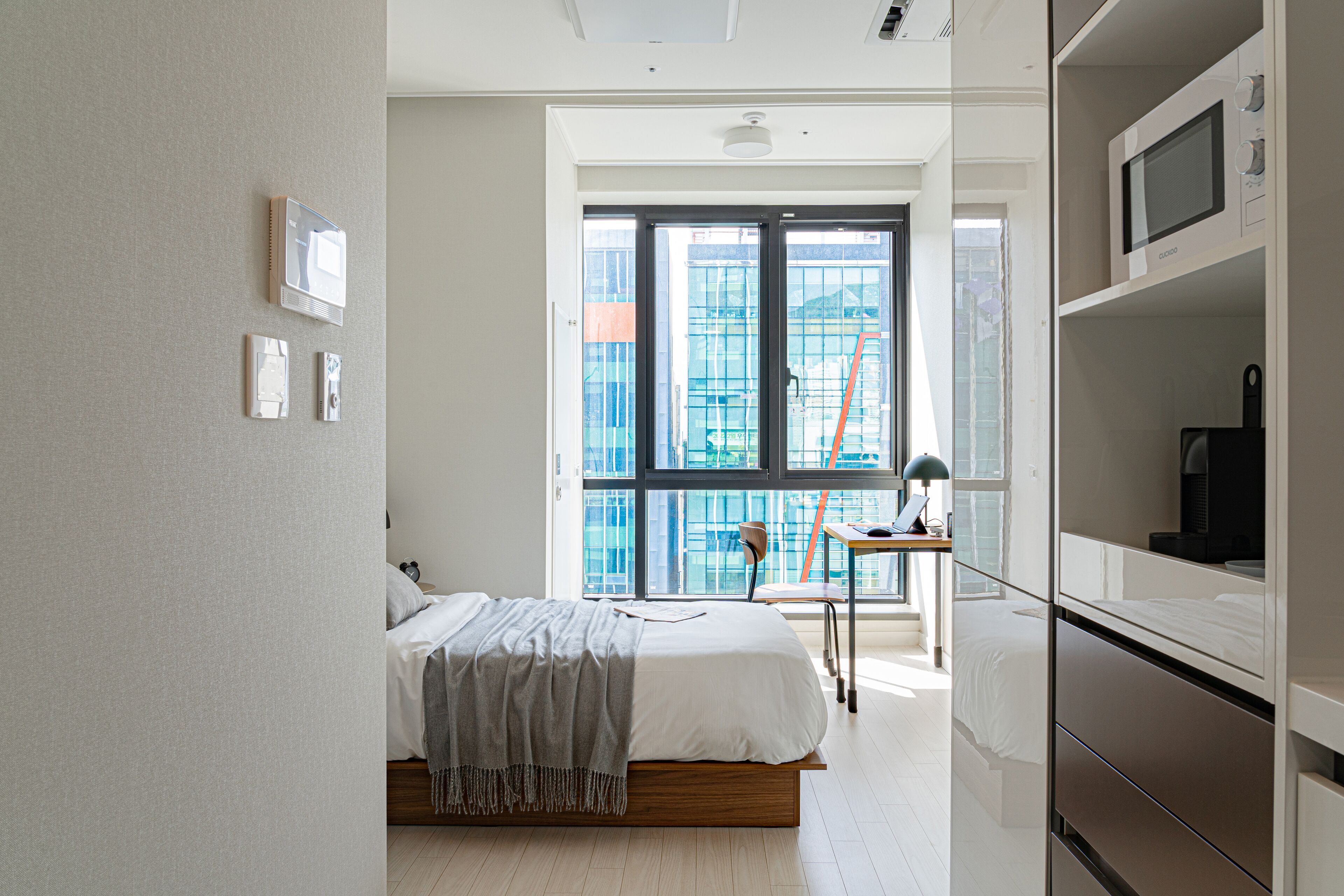 A modern bedroom with a bed, a desk, and a wardrobe.