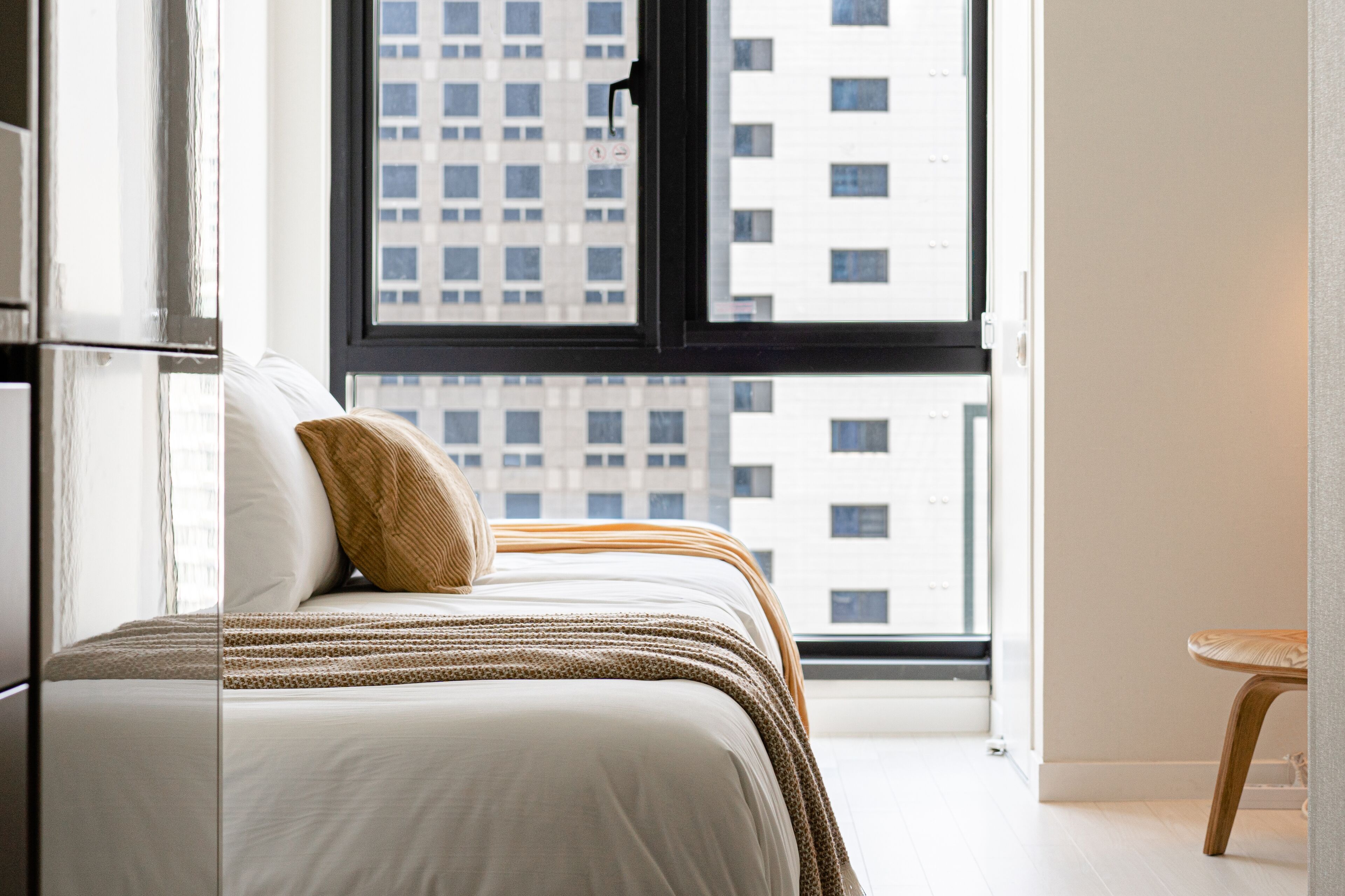 Een slaapkamer met een bed, een raam en uitzicht op gebouwen.