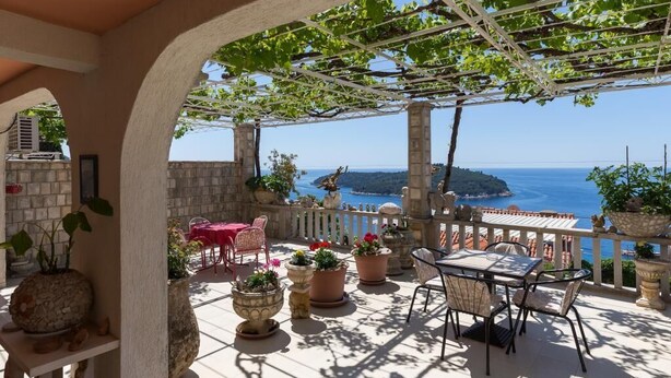 A terrace with a pergola, potted plants, and a table and chairs. - Apartment Horizont (Dubrovnik)