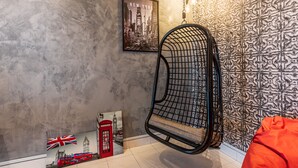 A room with a hanging chair, a framed cityscape poster, and a patterned wallpaper. - Conceptual Homestay 3BR 9PAX (Ampang)