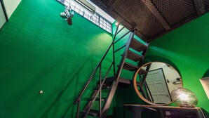 A green room with a metal staircase, a round mirror, and a door. - Conceptual Homestay 3BR 9PAX (Ampang)