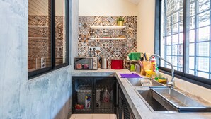 A kitchen with a tiled backsplash, a built-in oven, a sink, and a window with a view of buildings. - Conceptual Homestay 3BR 9PAX (Ampang)