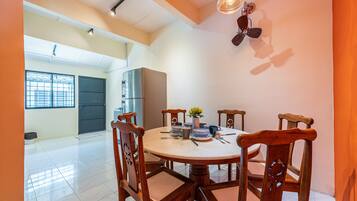 A dining area with a round table, wooden chairs, and a ceiling fan.