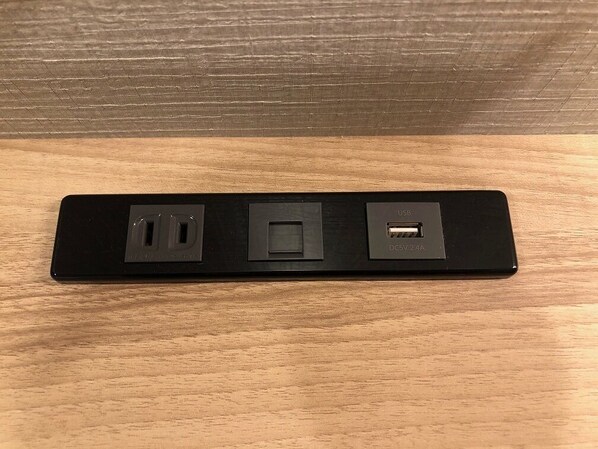 A black power strip with three USB ports and two standard electrical outlets on a wooden surface. - Smile Hotel Osaka Nakanoshima (Osaka)