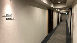 A hotel hallway with numbered doors, carpeted floors, and a ceiling with recessed lighting.