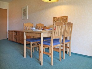Ein Essbereich mit einem Holztisch und Stühlen, einem gewebten Wandbehang und einem gerahmten Bild an der Wand.